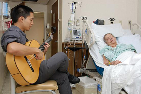 Student plays the guitar for a patient